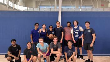 A group of people standing and kneeling on a basketball court.
