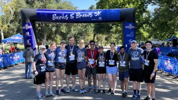 A group of people standing in line with race medals at the finish line.