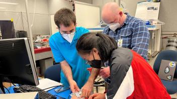 Adam, Cordell, and Miranda performing CubeSat integration at JSC